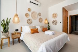 a bedroom with a large white bed with orange pillows at Villa Casa Goya - Lofty Pool Villa Near The Beach in Vibrant Legian in Legian +17 photos