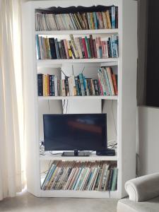 a white book shelf with a tv and dvds at Sea Spray Self Catering in Agulhas +15 photos