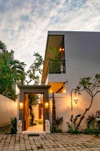 a white house with a balcony and a door at Sister Suites in Seminyak