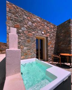 a hot tub in front of a stone building at Agathia Resort in Schinoussa