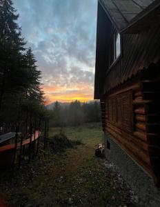 een zonsondergang achter een hut met een bank ernaast bij RETRO CHATA Kubínska in Dolný Kubín