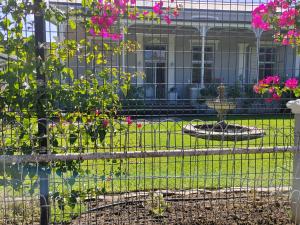 a fence in front of a garden with pink flowers at La Damon 2 in Paarl +7 photos