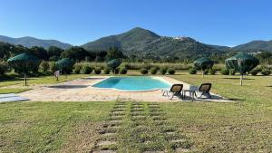 una piscina en un campo con 2 sillas y montañas en Maremma Toscana a Scarlino elegante appartamento, en Scarlino