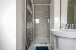 a white bathroom with a shower and a sink at 3 Bedroom House in Ebbsfleet in Swanscombe +33 photos