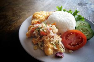 a plate of food with rice and a tomato at Rumah Bata Salatiga in Salatiga