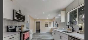 a large kitchen with white cabinets and a sink at Mabel place in Lakewood