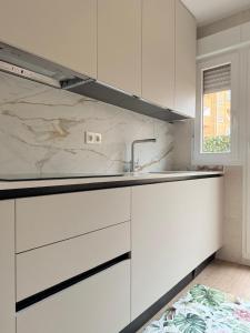 a white kitchen with white cabinets and a sink at Reformado Centro con Terraza in Castro-Urdiales
