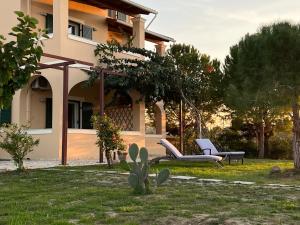 a house with two chairs and a cactus in the yard at Dimitra Houses 2 - Seaside in Lefkimmi