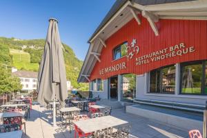 VionnazManoir du Vignoble的一间带遮阳伞和桌椅的餐厅