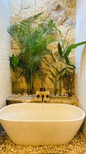 y baño con bañera y pared de piedra. en Best Deals - New Fancy 2BR Private Pool Villa, en Uluwatu
