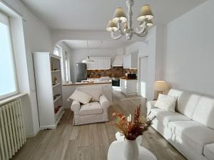 a living room with white furniture and a kitchen at Casa vacanze Orobie in Villa di Tirano