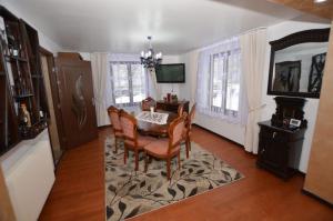 Un comedor con mesa y sillas y un televisor. en Cabana Briana, en Borşa