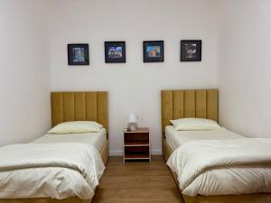 - 2 lits dans une chambre avec des photos sur le mur dans l'établissement Vivo Apartment, à Durrës