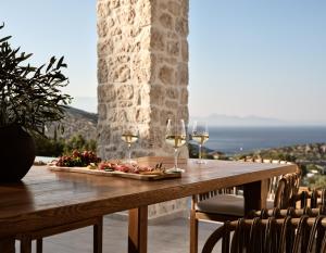 a table with wine glasses and a plate of food at Zakynthos Villa with Stunning Views in Agios Nikolaos