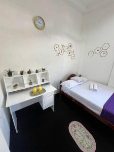 a bedroom with a bed and a desk with a clock on the wall at The Hotel Ujaliya in Ratgama Hegoda