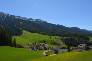 un piccolo villaggio in una valle verde con montagne di Fallerhof a Villnoss