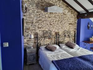 una camera da letto con due letti di fronte a un muro di pietra di Hotel Rural La Casa Encanto a Espinosa de los Monteros