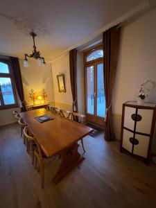 a dining room with a wooden table and chairs at Maison d hotes villa les pervenches in La Chaux-de-Fonds +3 photos