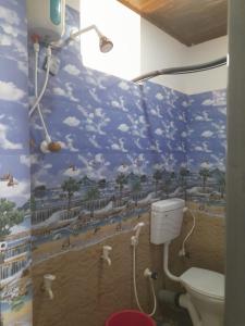 a bathroom with a mural of a beach with a toilet at Candle wood Beach Stay in Gokarn