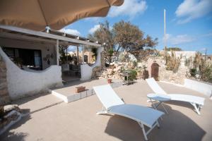 two white chairs and an umbrella on a patio at Villa a picco sul mare - Cala Creta in Lampedusa
