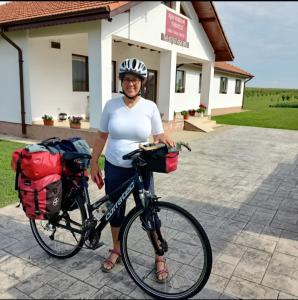 a woman standing with a bike in front of a building at Family House Pristol in Pristol