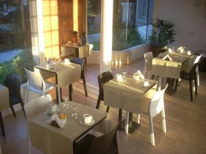 a restaurant with white tables and chairs in a room at Hotel Queguay in Colón