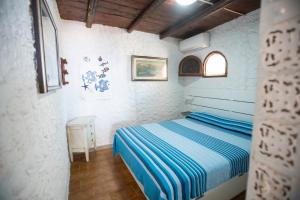 a bedroom with a bed with a blue striped sheets at Villa a picco sul mare - Cala Creta in Lampedusa