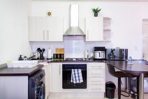 a kitchen with white cabinets and a stove top oven at Serenity Escape Windhoek in Windhoek