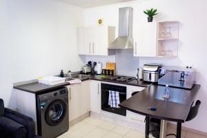 a kitchen with a washing machine and a table at Serenity Escape Windhoek in Windhoek +14 photos