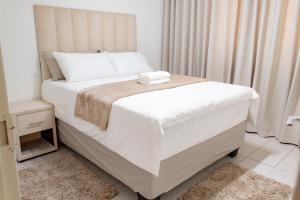 a bedroom with a large white bed with white sheets at Serenity Escape Windhoek in Windhoek