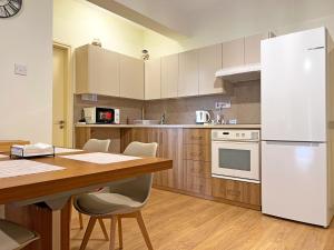 a kitchen with a wooden table and a white refrigerator at Albert's Apartment Mackenzie 001 in Larnaka