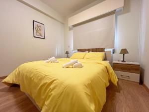 a bedroom with a yellow bed with towels on it at Albert's Apartment Mackenzie 001 in Larnaka
