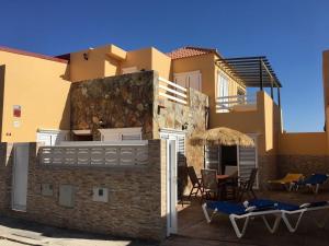 a building with a patio with chairs and an umbrella at Urb Bella Vista 44 in Costa Calma