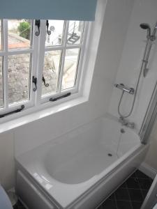 a white bath tub in a bathroom with a window at Bosun's Rest in Beer +10 photos