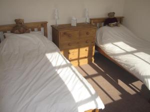 two beds in a bedroom with two teddy bears on them at Bosun's Rest in Beer
