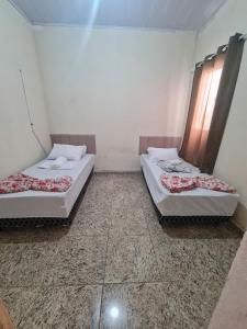 two beds sitting in a room with two windows at Casa de Maria in Aparecida