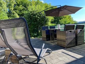a folding chair and an umbrella on a patio at Ferienhaus Mayer Dahn Wohnung Neven in Dahn +2 photos