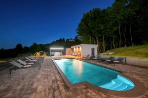 a swimming pool with chairs and a building at Villa Alea in Vinogradi Ludbreški