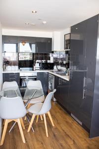 una cocina con sillas blancas y armarios negros en Sidemersey Livings - 2 Bedroom Central Apartment with views, en Liverpool