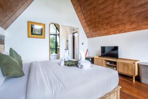 a bedroom with a bed with white sheets and a tv at green slope villa glamping in Gitgit