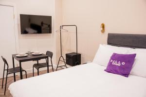 ロンドンにあるPillo Rooms Apartments - Chelseaのベッドルーム1室(紫色の枕が付いたベッド1台付)