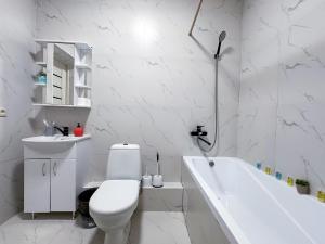 ein weißes Badezimmer mit Toilette und Badewanne in der Unterkunft Просторная квартира для большой компании in Almaty + 39 Fotos