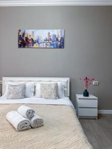 ein weißes Schlafzimmer mit einem Bett mit Handtüchern darauf in der Unterkunft Просторная квартира для большой компании in Almaty