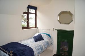 a bedroom with a bed and a window and a mirror at 2 Buckatree Cottage in Wellington