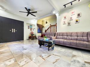 Una sala de estar con un sofá y un ventilador de techo. en IPOH Taman Pelangi Double Storey Homestay, en Ipoh