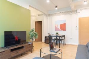 a living room with a couch and a tv and a table at Samyan Story Boutique Hotel in Bangkok