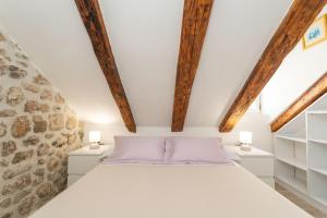 Schlafzimmer mit einem weißen Bett und Holzbalken in der Unterkunft ZUZORI apartments in Dubrovnik
