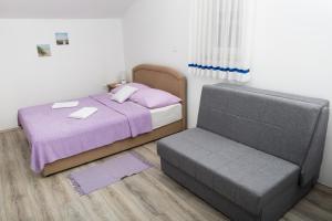 a bedroom with a bed and a chair at apartments VIGI - III in Povljana