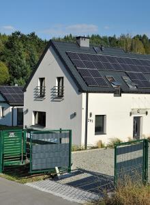 a white house with solar panels on top of it at Dom Nad Potokiem Średnia Wieś in Hoczew