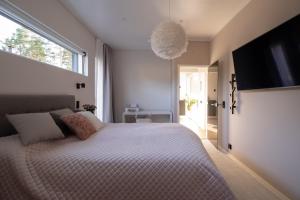 a bedroom with a large bed and a flat screen tv at Forest Dream House in Naantali